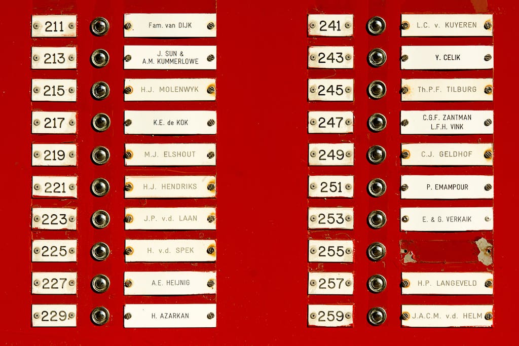 Close-up of a red doorbell panel with multiple nameplates and buttons in a building.