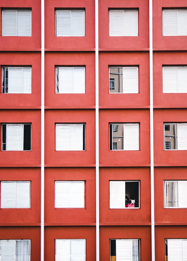 Geometric facade of a red apartment building with repeating window patterns.