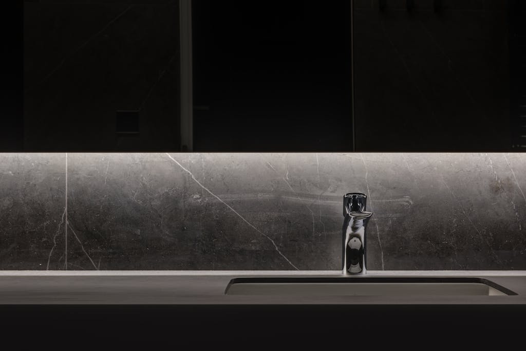 Sleek minimalist bathroom with a modern illuminated faucet and washbasin.